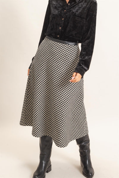 model wearing a black top and checkered skirt with a light background