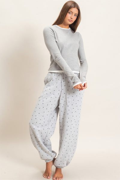model wearing a gray top with star print joggers in front of a light background