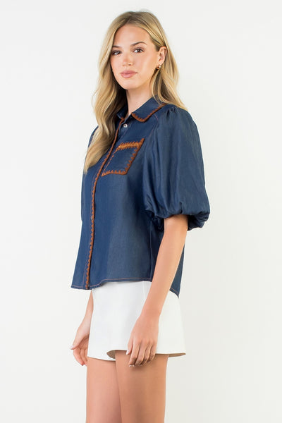 Woman wearing a blue blouse with orange accents on a white background