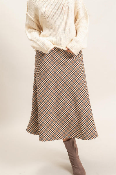 model wearing ivory sweater and checkered skirt with a light background