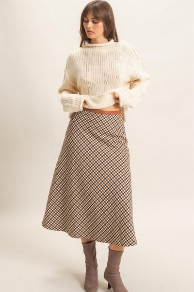 model wearing ivory sweater and checkered skirt with a light background
