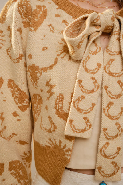 Close-up of a beige cardigan with brown pattern and matching scarf.