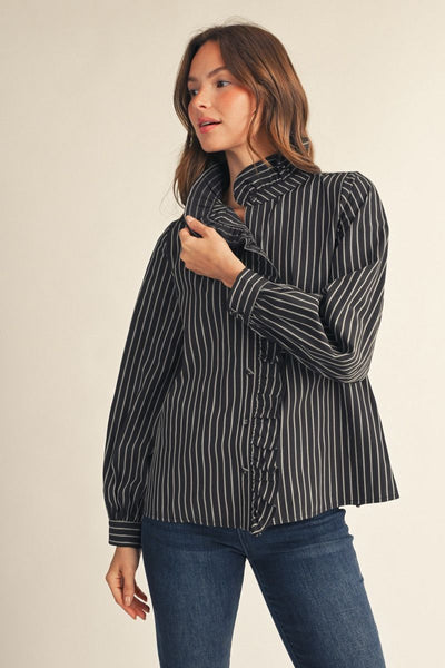 model wearing a black & white striped top with ruffle down the front and jeans with a beige background