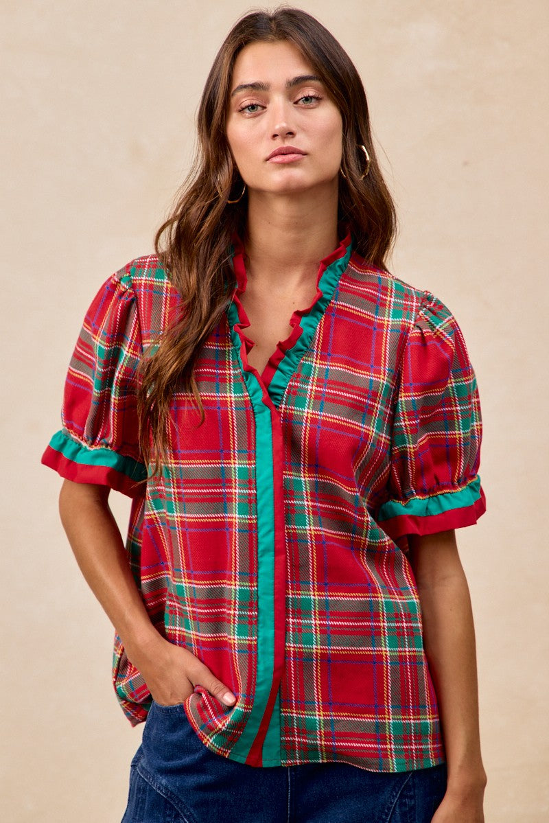 Woman wearing a red plaid shirt with green accents against a beige background