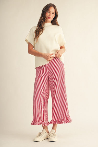 Woman wearing a white top and red striped pants on a plain background