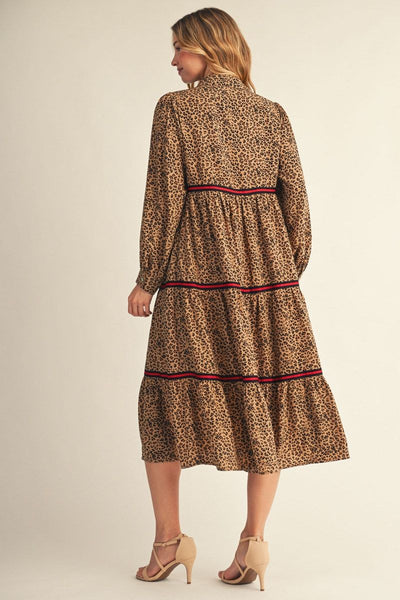 back of model wearing long sleeve leopard print dress with black/red contrast detail with a beige background