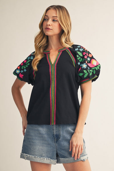 model wearing black top with embroidery & cuffed denim shorts