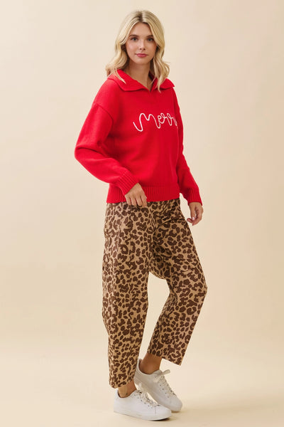 Woman wearing a red hoodie with text and leopard print pants on a beige background
