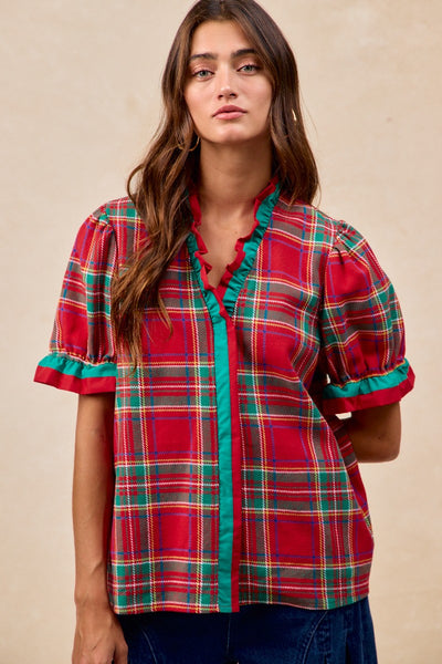 Woman wearing a red plaid shirt with green accents on a beige background