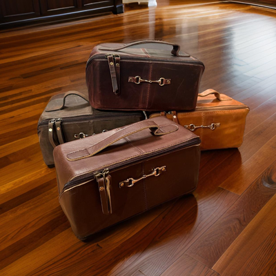 Four vintage-style leather suitcases stacked on a wooden floor