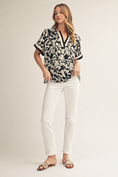 model wearing floral top & white pants