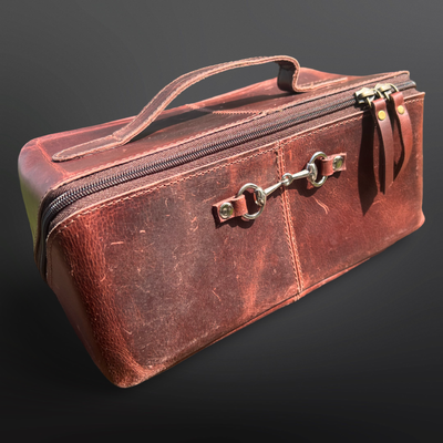 Brown leather case with a metallic clasp on a dark background