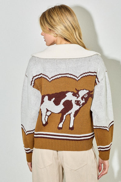 Person wearing a sweater with a cow design on a plain background