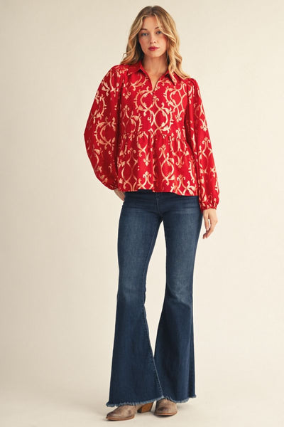 model wearing red and gold puff sleeve blouse with jeans and boots in front of a beige background