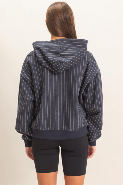 back of model wearing a navy striped hoodie with black shorts in front of a light background