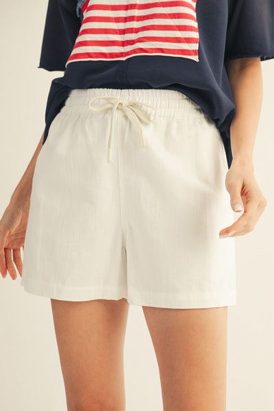 model wearing flag shirt & white drawstring shorts