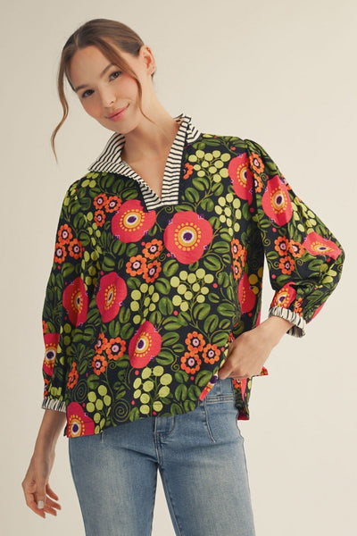 model wearing black stripe & dark floral blouse with denim pants on a light background