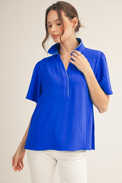 model wearing a royal blue v neck blouse with white pants