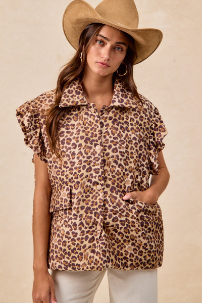 Woman wearing a leopard print top and beige hat against a beige background