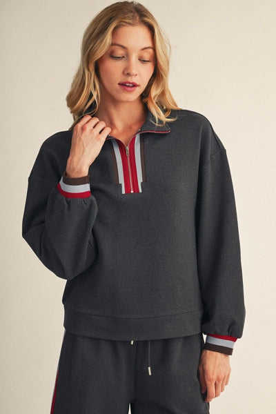 model wearing charcoal sweatshirt & sweatpants before a beige background
