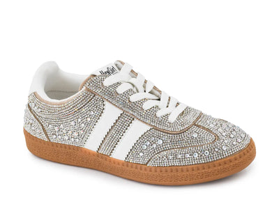 A low-top sneaker embellished with silver rhinestones, featuring white laces, a white side stripe design, a brown gum sole, and a white interior lining.