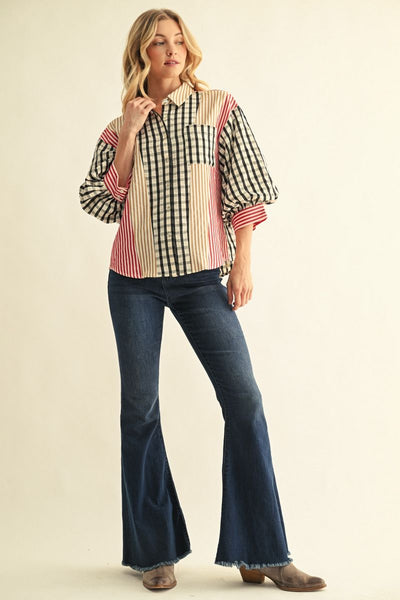 A woman modeling a bohemian-style striped button-down shirt with puff sleeves and dark blue flared jeans, standing against a plain cream background.