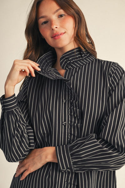 model wearing black & white striped blouse in front of a beige background