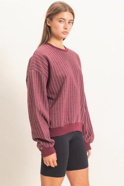 model wearing burgundy striped sweatshirt and black shorts with a light background
