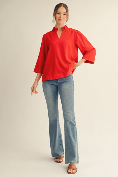 model wearing a red blouse & jeans with tan background