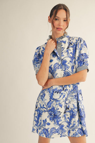 model wearing a blue & white floral dress with stripe accents on a light background