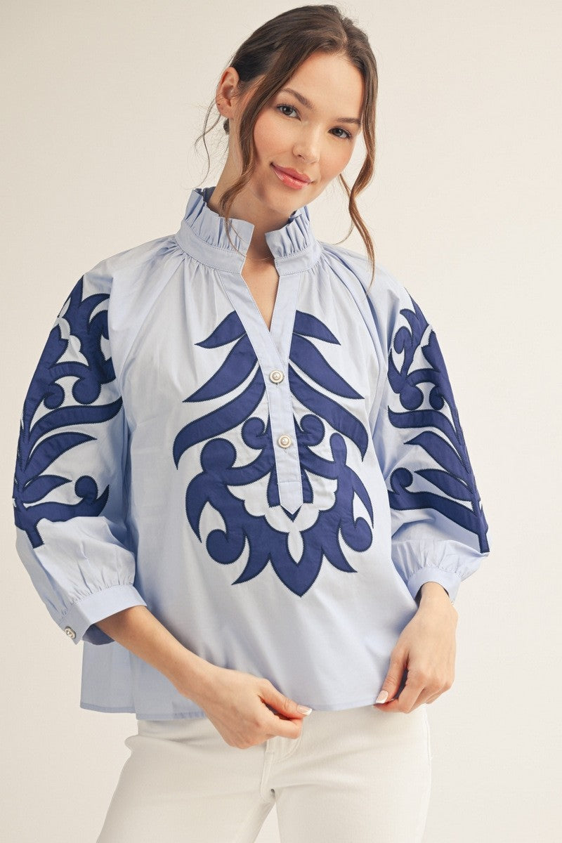 model wearing a blue Applique blouse & white pants