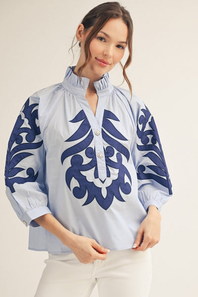 model wearing a blue Applique blouse & white pants