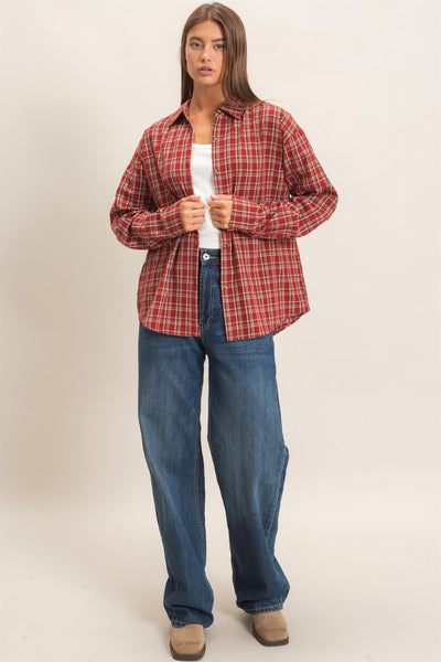 woman wearing a plaid shirt and jeans in front of a light background