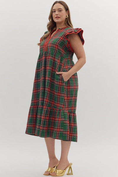 Woman wearing a green plaid dress with red accents on a white background