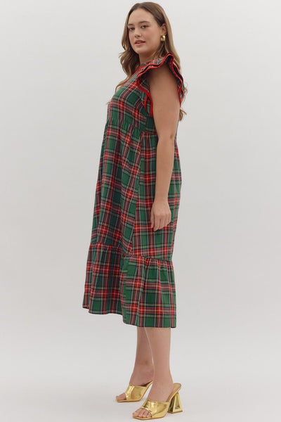 Woman wearing a green plaid dress with red accents on a white background