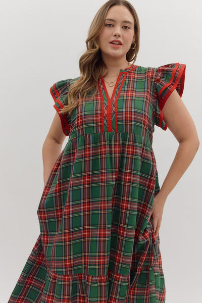 Woman wearing a green and red plaid dress with ruffled sleeves on a white background