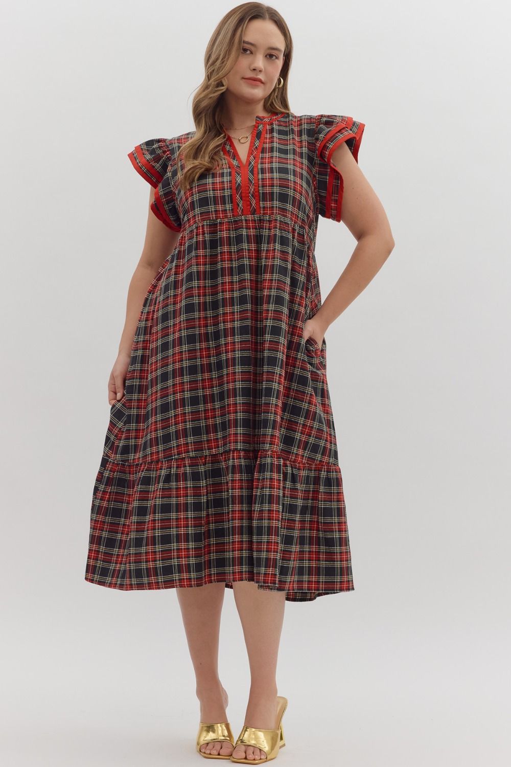 Woman wearing a plaid dress with red accents on a white background