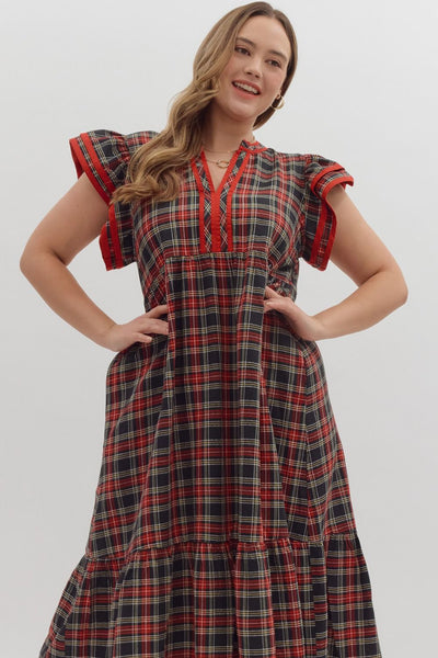 Woman wearing a plaid dress with red accents on a white background