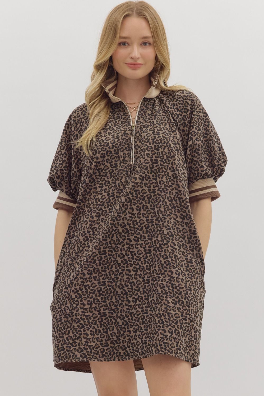 Woman wearing a leopard print dress with puff sleeves on a plain background