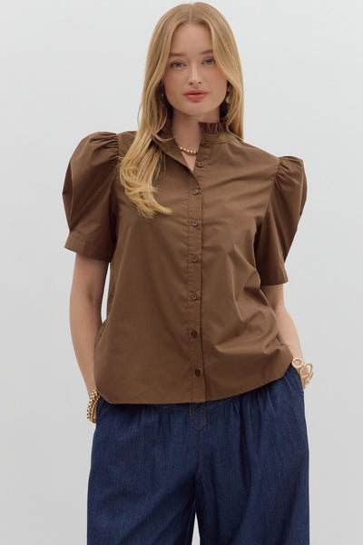 Woman wearing a brown blouse with puff sleeves and blue pants on a white background