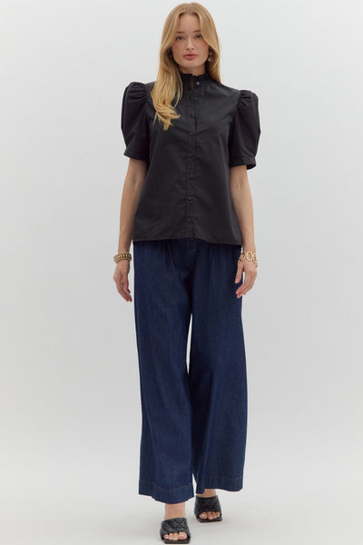 Woman wearing a black blouse and navy pants on a white background