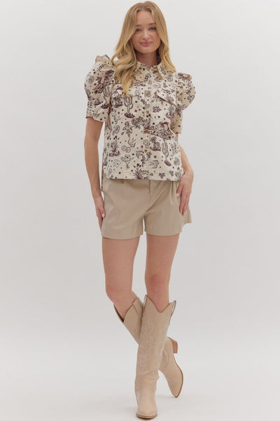Woman wearing a floral blouse, beige shorts, and beige knee-high boots on a white background