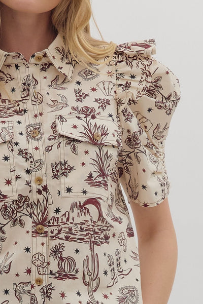 Close-up of a person wearing a patterned shirt with floral and animal designs on a plain background