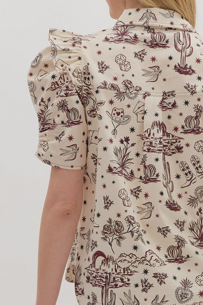 Close-up of a person wearing a patterned shirt with desert-themed designs on a plain background