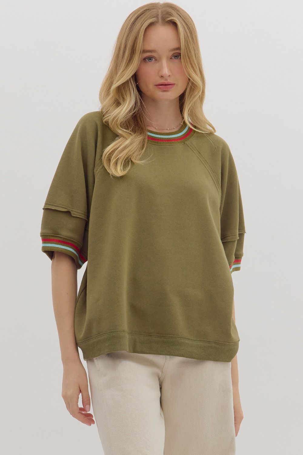 Woman wearing an olive green sweatshirt with colorful cuffs on a white background
