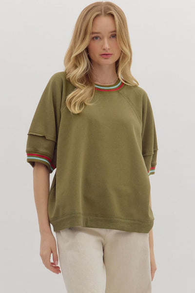 Woman wearing an olive green sweatshirt with colorful cuffs on a white background