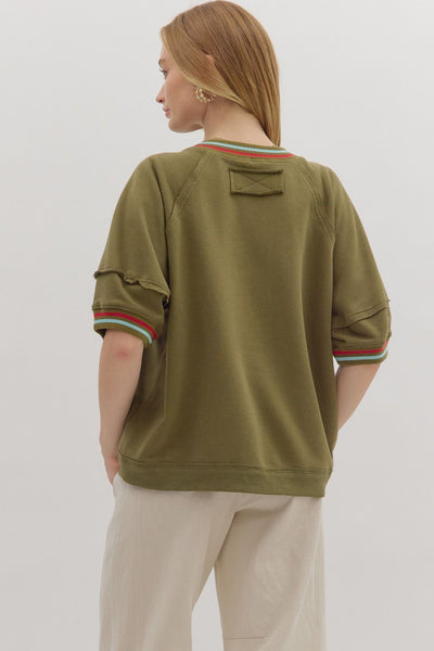 Person wearing a green sweatshirt with striped cuffs on a white background