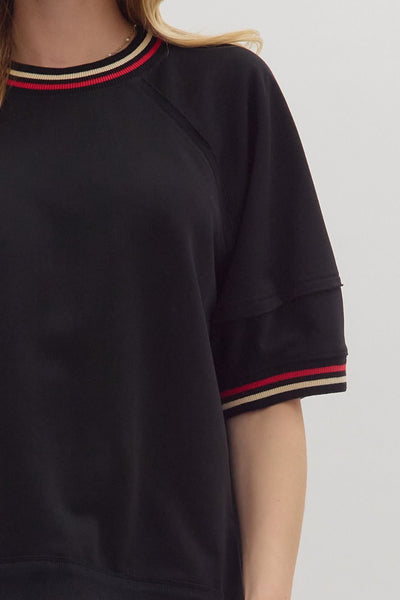 Black sweater with striped cuffs on a plain background