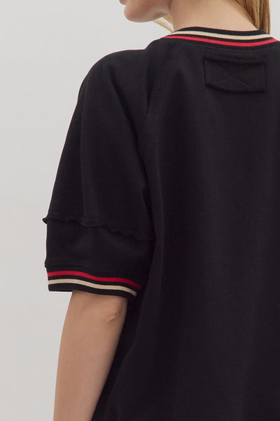 Black shirt with red and beige trim on a plain background