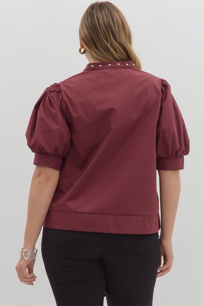 Person wearing a burgundy blouse with puff sleeves on a white background